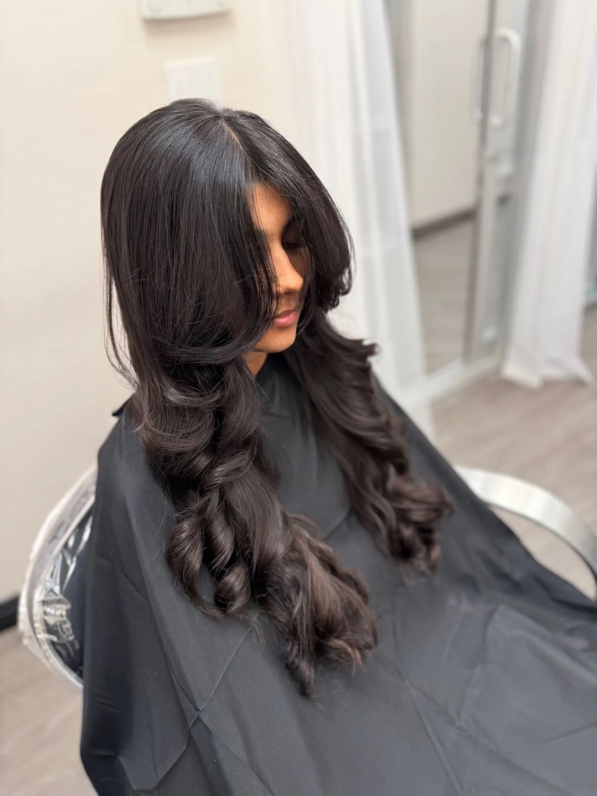 Cabello oscuro estilizado con rizos voluminosos y capas